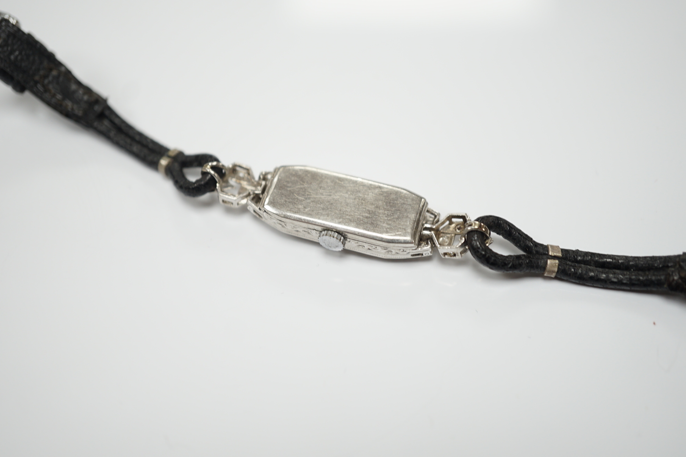 A lady's white metal (engraved platinum) and diamond cluster set manual wind cocktail watch, on a leather strap.